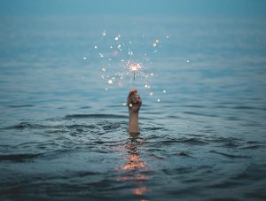 Hand Holding Sparkler Reaching Up Out Of Water